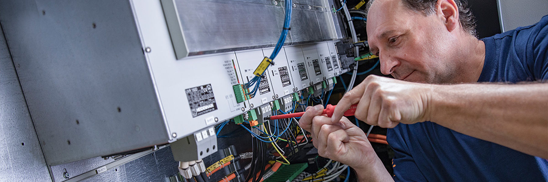 Techniker arbeitet an einer elektrischen Anlage mit Kabeln und Messgerät